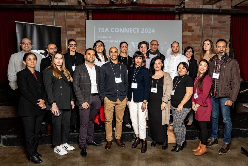 A group of twenty architectural professionals smiling at the Toronto Society of Architects Connect event for internationally-trained immigrant professionals.