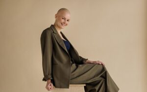 Julianna Kaiser sitting on a wooden chair. She is wearing a fashionable green outfit, smiling and posing for the professional photo shoot.
