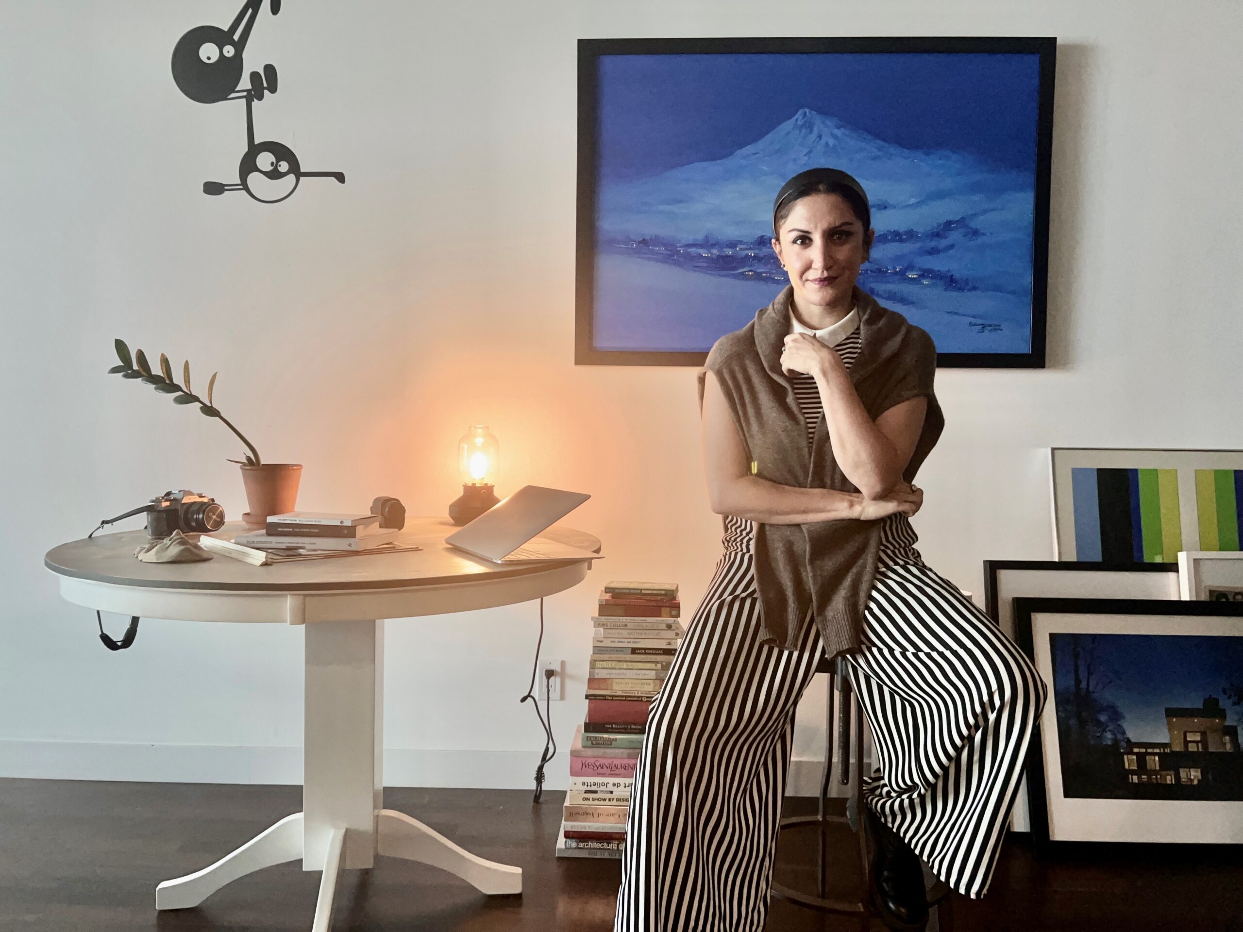 Sanam Samanian sitting in her workspace which has art and objects throughout it.